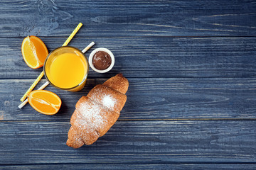 Wall Mural - Composition with fresh tasty crescent roll and orange juice on wooden background