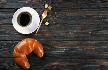 Poster - Composition with fresh tasty crescent roll and coffee on wooden background