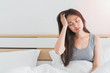 Young Asian woman feel headaches and discomfort on bed in white bedroom morning.Concept of women's health care.