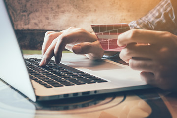 Man holding credit card while using laptop in home office.