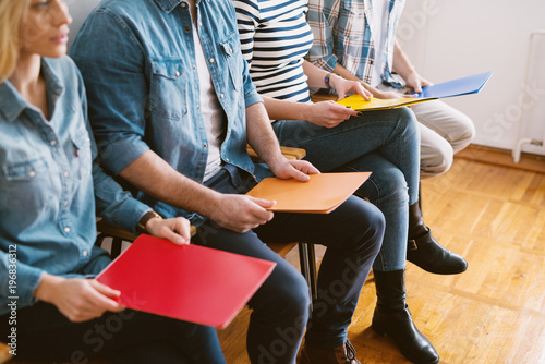 Fotografía Close up view of young people sitting in chairs with folders before the job interview in the waiting room