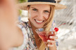 © WHstudio Leushin N - Adorable young woman with happy expression, holds fresh cherry cocktail, makes selfie, pose outdoor, has delighted look, glad to have summer rest in resort country. Happiness and recreation concept