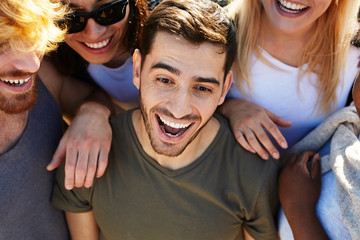 Wall Mural - Excited guy and his friends enjoying summer day or vacation on the beach