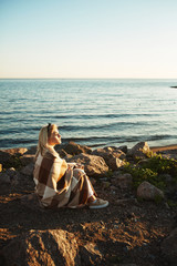 Wall Mural - Blonde girl enjoying summer evening by seaside while sitting by water