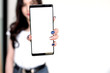 Young woman showing a white screen smartphone . Focus on smartphone