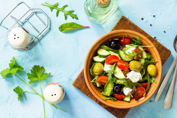 Wall Mural - Greek salad with fresh vegetables, feta cheese and black olives on a blue stone or concrete table. Diet, concept of vegetarian food. Copy space, top view flat lay background.