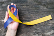 World down syndrome day with blue yellow awareness ribbon bow color on helping hand for raising support on patient with down syndrome illness disability and Thoracic Outlet Syndrome - (TOS)