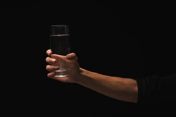 Wall Mural - Male hand holding glass of water isolated on black