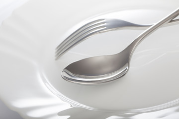 Wall Mural - Empty plate with spoon and fork on a white background