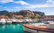 Low angle view on Chateau de Cassis castle on top of hill and close up of boats moored in harbour on bright sunny day in Cassis, France