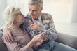 © Yakobchuk Olena - Mature man talking to his wife and showing forefinger while she is holding tablet and looking at him with smile