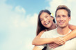 © Maridav - Happy couple hugging in summer blue sky background. Smiling young people tourists on travel vacation. Asian girl piggyback on man. Healthy lifestyle.
