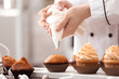 © Africa Studio - Chef decorating tasty cupcakes with cream at table
