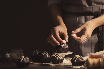 Sticker - Woman decorating tasty cupcake at table