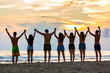 © william87 - Group of friends raising hands on the beach at sunset