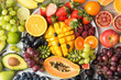 Healthy food background, assortment of fruits in rainbow colours on the off white table, top view, selective focus