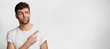 © wayhome.studio  - Puzzled blue eyed handsome young bearded man poses agianst blank copy space, dressed casaully, indicates with fore finger aside, raises eyebrows in bewilderment. Advertisment and people concept