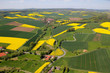 Luftaufnahme einer deutschen Mittelgebirgs-Landschaft im Frühling mit vielen Rapsfeldern