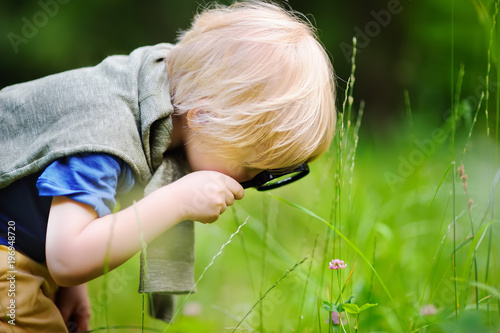 Cuadros en Lienzo Charming kid exploring nature with magnifying glass