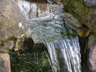 Stream between two boulders, a miniature waterfall