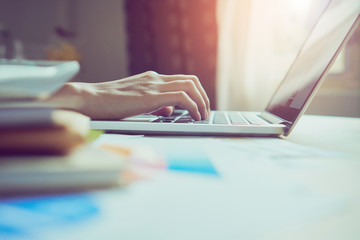 businessman hand working laptop on wooden desk in office in morning light. vintage effect