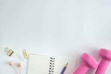 Styled stock photography of fitness equipment dumbbells notepad pencil and earphone on white background. Flat lay.