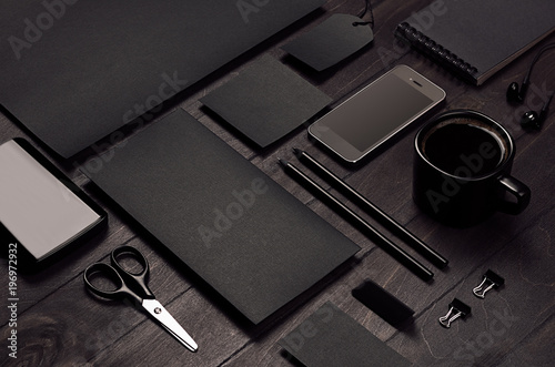 Fotografía Blank black corporate stationery with phone on dark stylish wood background, inclined, closeup