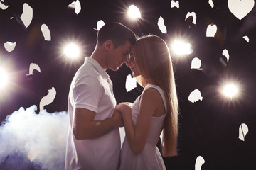 Poster - Young loving couple on dark background with backlit and smoke