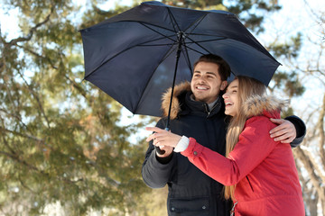 Poster - Young romantic couple with umbrella in park