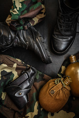 Army uniform military boots, boots, pants, bowler, pistol in holster on a dark background with copy space workspace flat lay top view