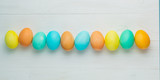 Fototapeta  - colored Easter eggs on a white table, top view