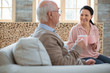 © zinkevych - Hot tea. Joyful jolly caregiver gossiping with senior man while grinning and enjoying tea