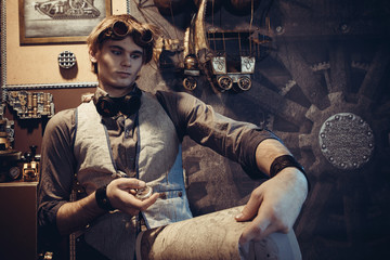 Wall Mural - Portrait of a young mad scientist traveler in a steampunk style suit with a card.