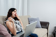 © Iulia - Beautiful young woman sitting on the sofa with laptop on her knees in home interior. Yawning while working. Work concept