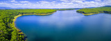 Fototapeta Las - Aerial panorama of beautiful blue lake and forest under white fluffy clouds in Australia