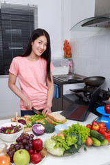 Sticker - woman cooking and looking with laptop in kitchen room