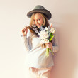 © AnastazjaSoroka - A young beautiful girl with blond dissolved long hair, a felt hat on her head, keeps spring flowers in her hands on a sunny day. Women's Day.