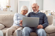© zinkevych - Quality time. Upbeat senior husband and wife holding a laptop in their lap and surfing the Internet together while sitting on the sofa in their living room