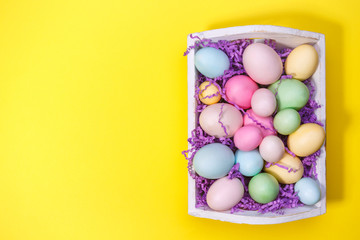 Wall Mural - Multicolor eggs in a white tray. Creative Easter concept. Modern solid yellow background.