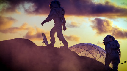 Wall Mural - two silhouettes of the astronauts explore red rocky alien planet. in the background sunset with base