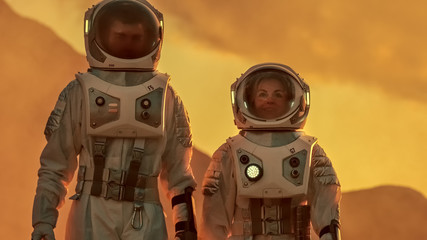 Wall Mural - two astronauts wearing space suits walk exploring mars/ red planet. space travel, exploration and co