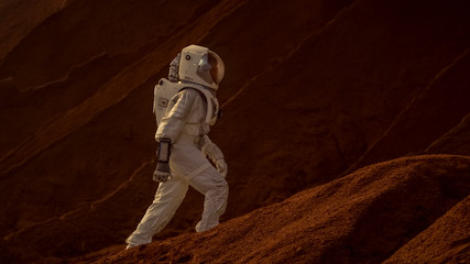 Wall Mural - astronaut goes up the mountain to explore red planet/ mars. in the background his base and ai powere