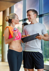 Canvas Print - smiling young woman with personal trainer in gym