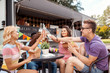 © Syda Productions - friends clinking drinks and eating at food truck