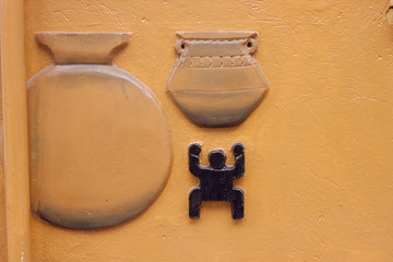 Yellow house pre-columbian facade. Handmade facade background. Facade with art design of two ancient jars and a little indigenous man.