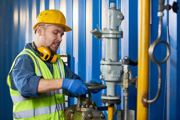 Waist up portrait of young man wearing hardhat working with plumbing at modern plant, copy space