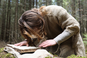 A man in a cassock spends a ritual in a dark forest