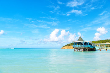 Sea beach with wooden shelter on sunny day in antigua. Pier in turquoise water on blue sky background. Summer vacation on caribbean. Wanderlust, travel, trip. Adventure, discovery, journey