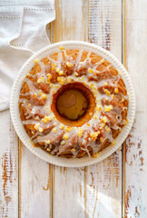 Wall Mural - Easter Yeast cake on a white plate  on a wooden table, top view. Traditional Easter cake with raisins and icing with candied orange peel