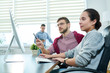 © Seventyfour - Young Caucasian woman sitting at office table with bearded male coworker and looking at computer screen